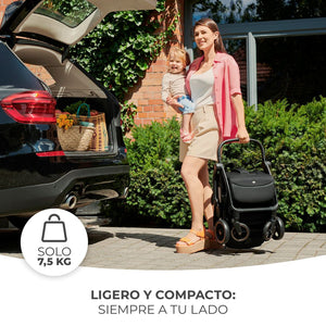 Coche de paseo Kinderkraft APINO de solo 7,5 kg: mamá cargando el coche plegado con una mano junto al maletero del auto