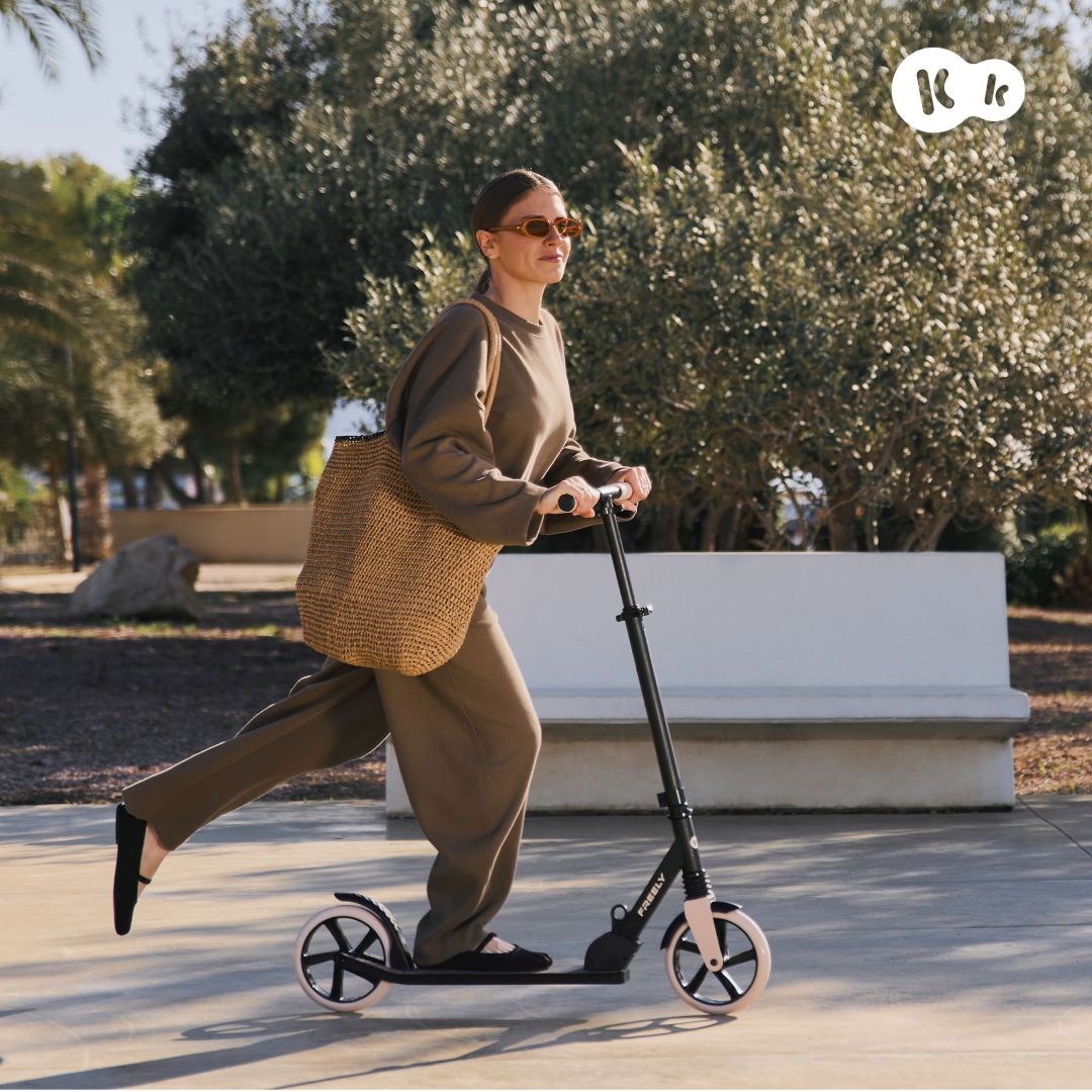 Mujer adulta usando scooter Kinderkraft FREELY beige en parque, scooter para adultos hasta 100 kg con manillar ajustable y ruedas de amortiguación