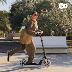 Mujer adulta usando scooter Kinderkraft FREELY beige en parque, scooter para adultos hasta 100 kg con manillar ajustable y ruedas de amortiguación
