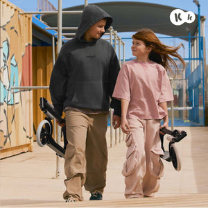 Dos niños caminando con scooter Kinderkraft FREELY plegado en mano, solo 4,9 kg, ideal desde 5 años hasta 100 kg