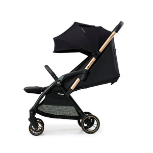 Coche Travel System Kinderkraft APINO negro con respaldo reclinado, capota grande y ruedas antipinchazos con detalle dorado, vista lateral