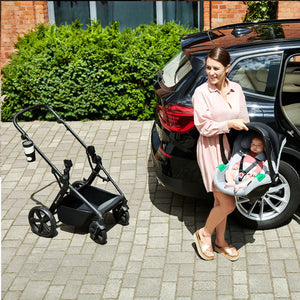 Mamá usando el travel system Kinderkraft NEWLY: retira la silla nido MINK PRO del auto para fijarla al chasis del coche de paseo